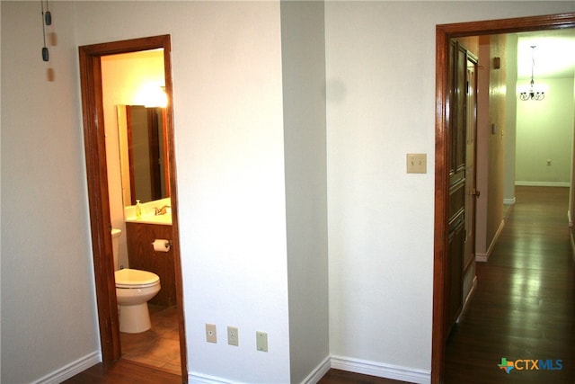 hallway featuring dark hardwood / wood-style flooring and an inviting chandelier