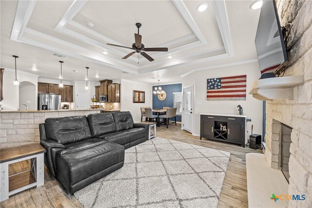 3424 Waggoner Dr, Belton, TX 76513 - living area featuring a tray ceiling, light wood-style floors, ceiling fan, a fireplace, and crown molding