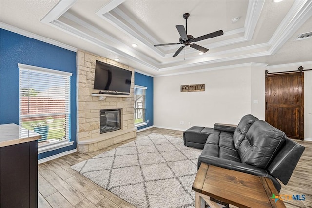 3424 Waggoner Dr, Belton, TX 76513 - living area with a tray ceiling, ornamental molding, a barn door, a ceiling fan, and a stone fireplace