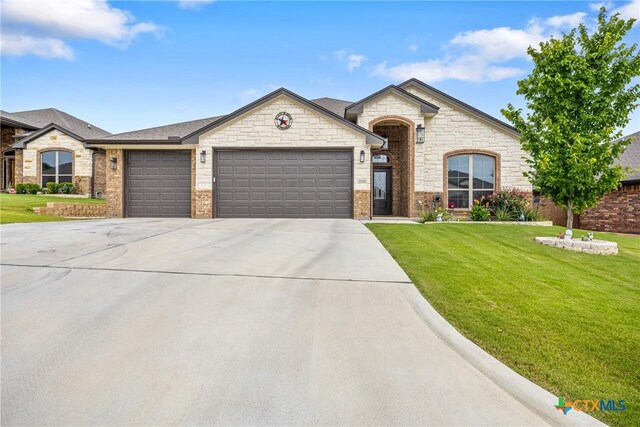 3424 Waggoner Dr, Belton, TX 76513 - french provincial home featuring an attached garage, concrete driveway, a front lawn, stone siding, and brick siding