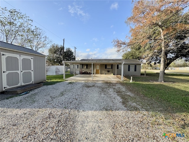 view of front of house featuring an outdoor structure, a front yard, a shed, a patio area, and gravel driveway