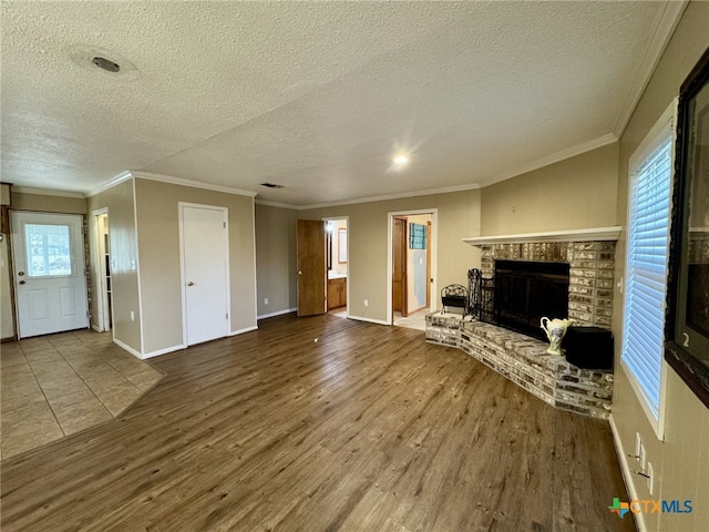 unfurnished living room featuring baseboards, a brick fireplace, wood finished floors, and crown molding