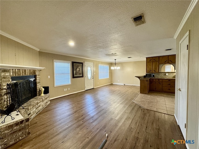 unfurnished living room featuring a brick fireplace, visible vents, dark wood finished floors, and crown molding