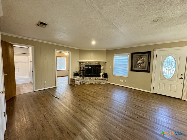 unfurnished living room featuring plenty of natural light, a fireplace, visible vents, and wood finished floors