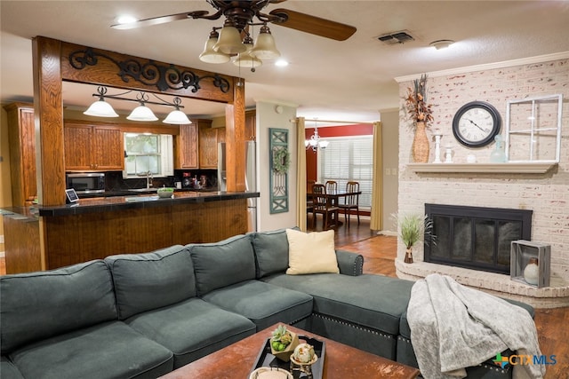 living room featuring a wealth of natural light, ceiling fan with notable chandelier, and light hardwood / wood-style flooring