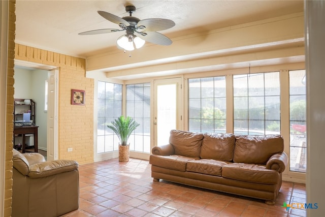 living room with ceiling fan, a healthy amount of sunlight, and brick wall