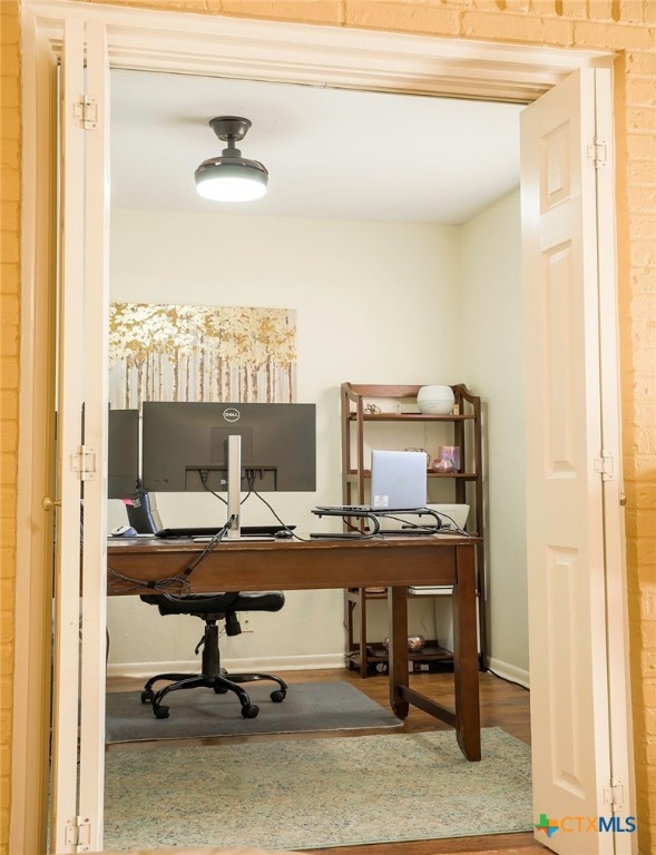 office featuring hardwood / wood-style floors and brick wall