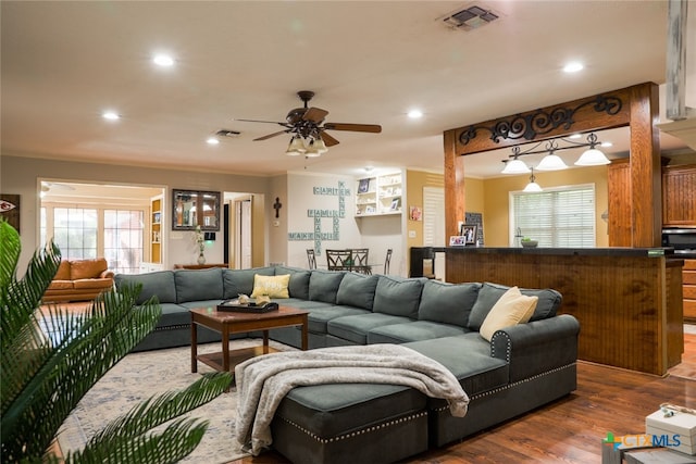 living room featuring ornamental molding, wood-type flooring, and ceiling fan