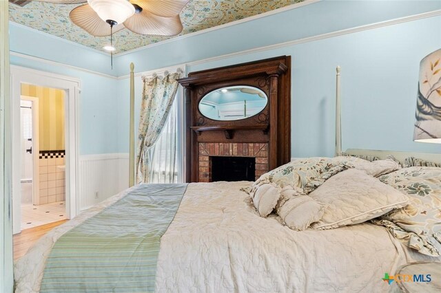 6 Carriage Sq, Waco, TX 76708 - bedroom with wainscoting, ceiling fan, ensuite bath, ornamental molding, and a brick fireplace