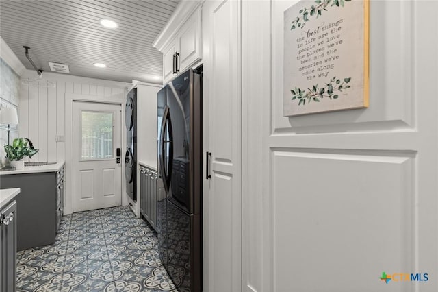 6 Carriage Sq, Waco, TX 76708 - kitchen featuring light tile patterned floors, light countertops, white cabinets, stacked washer and dryer, and freestanding refrigerator