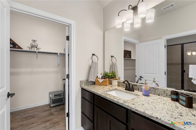 220 Bolivar Way Unit 101, San Marcos, TX 78666 - full bathroom featuring vanity, wood finished floors, baseboards, tiled shower, and a spacious closet