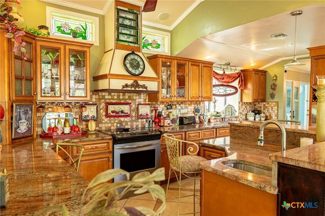 kitchen featuring dark stone counters, electric stove, decorative backsplash, sink, and pendant lighting