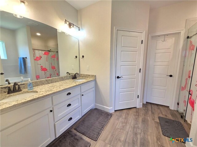 2635 Belle Hubbard Trl, Belton, TX 76513 - full bathroom featuring double vanity, curtained shower, wood finished floors, and baseboards