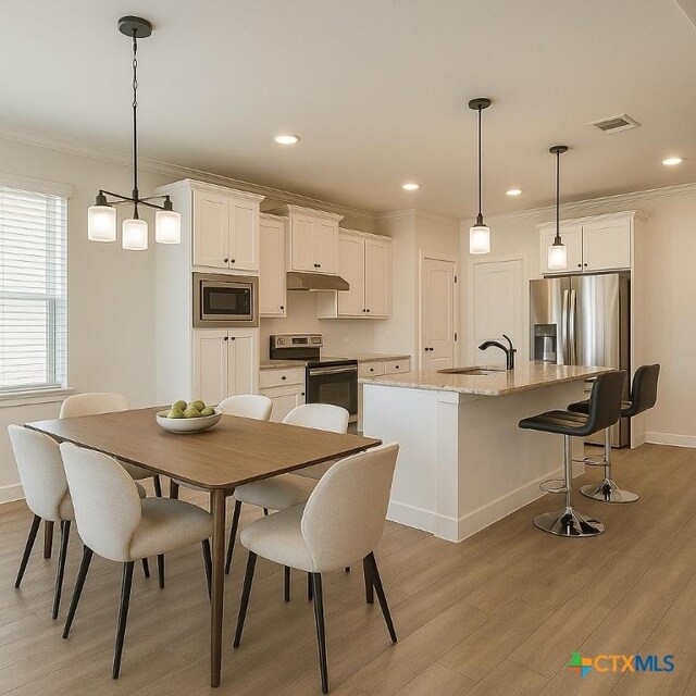 2635 Belle Hubbard Trl, Belton, TX 76513 - kitchen with appliances with stainless steel finishes, under cabinet range hood, ornamental molding, a sink, and light wood-style flooring