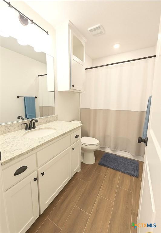 2635 Belle Hubbard Trl, Belton, TX 76513 - full bath featuring vanity, toilet, wood finish floors, and a shower with shower curtain