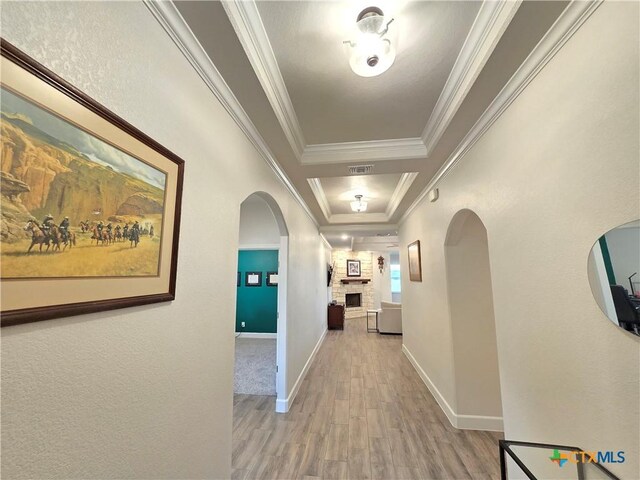 2635 Belle Hubbard Trl, Belton, TX 76513 - hallway featuring light wood finished floors, arched walkways, a tray ceiling, crown molding, and baseboards