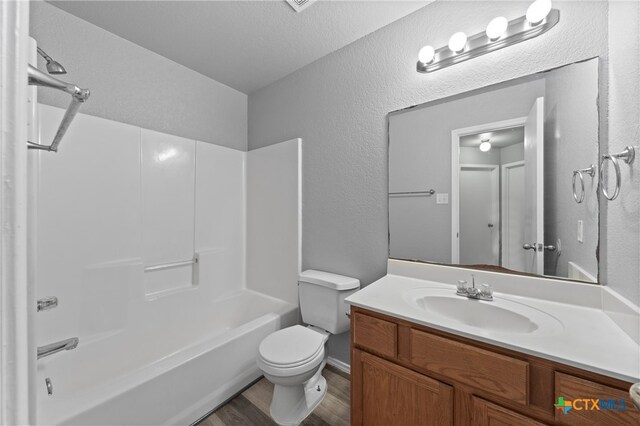 full bathroom featuring a textured ceiling,  shower combination, wood-type flooring, vanity, and toilet