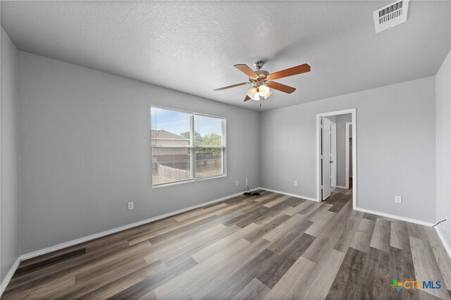 empty room with a textured ceiling, hardwood / wood-style flooring, and ceiling fan