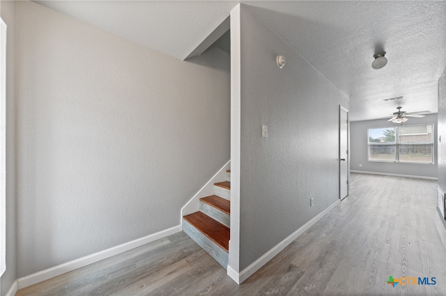 stairs with hardwood / wood-style floors, ceiling fan, and a textured ceiling