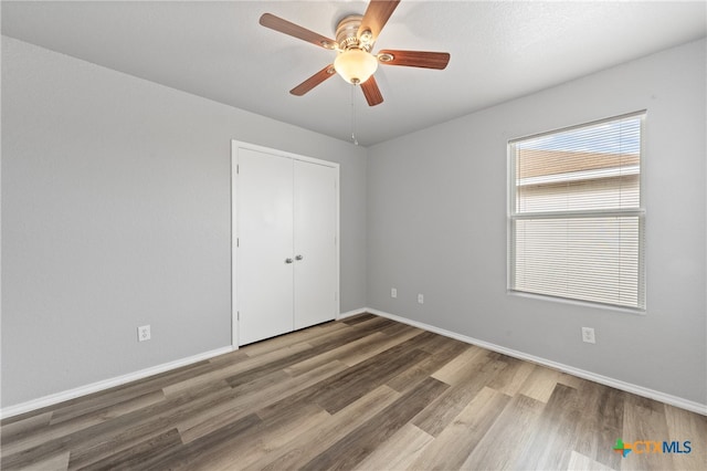 unfurnished bedroom featuring a closet, wood-type flooring, and ceiling fan