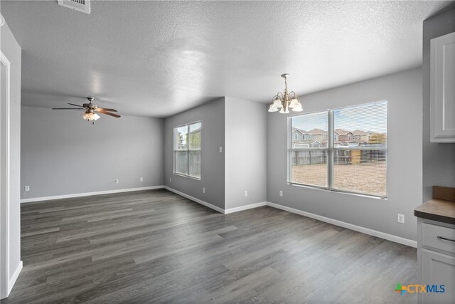 interior space featuring ceiling fan with notable chandelier, a textured ceiling, and dark hardwood / wood-style flooring