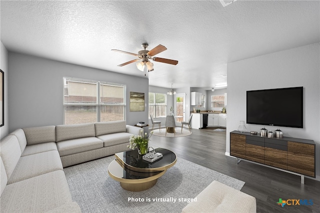 living room with dark hardwood / wood-style flooring, a textured ceiling, and ceiling fan with notable chandelier