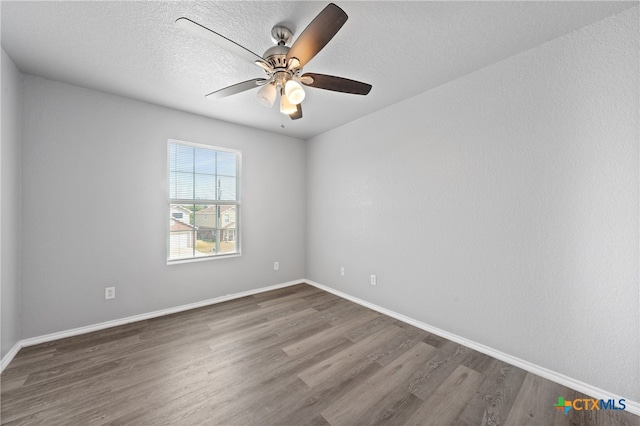 spare room featuring dark wood-type flooring, ceiling fan, and a textured ceiling