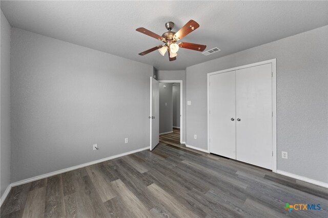 unfurnished bedroom featuring ceiling fan, a closet, and dark hardwood / wood-style flooring