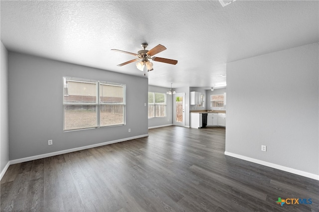 unfurnished living room featuring ceiling fan with notable chandelier, a textured ceiling, and dark hardwood / wood-style flooring