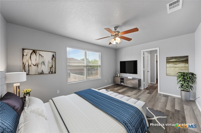 bedroom featuring a textured ceiling, wood-type flooring, and ceiling fan