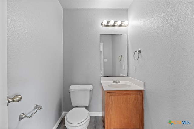 bathroom with wood-type flooring, toilet, and vanity