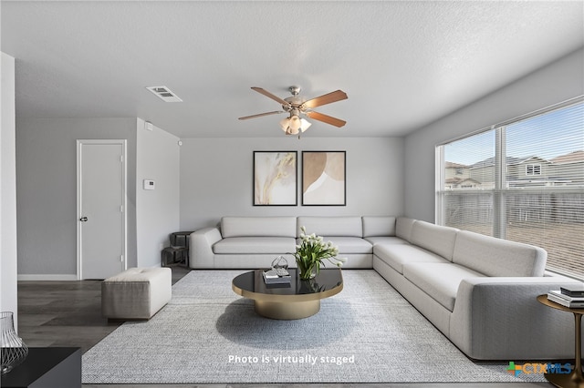 living room featuring wood-type flooring, ceiling fan, and a textured ceiling