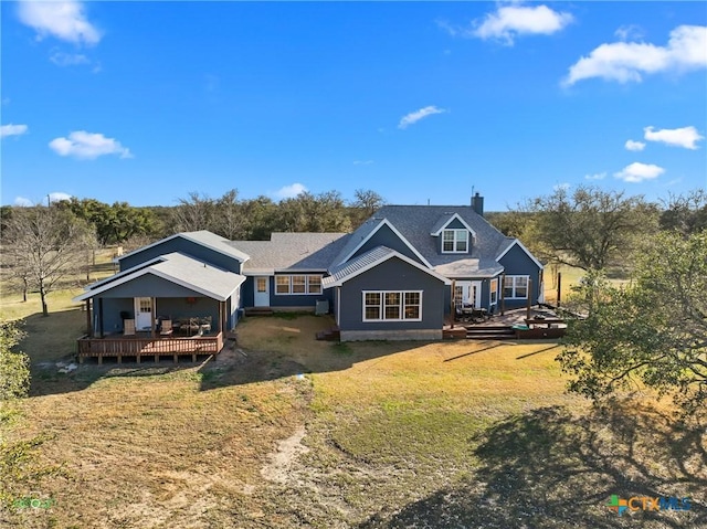 back of property with a chimney, a wooden deck, and a yard