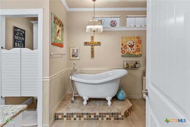 bathroom featuring crown molding, a freestanding tub, wood finish floors, and wainscoting