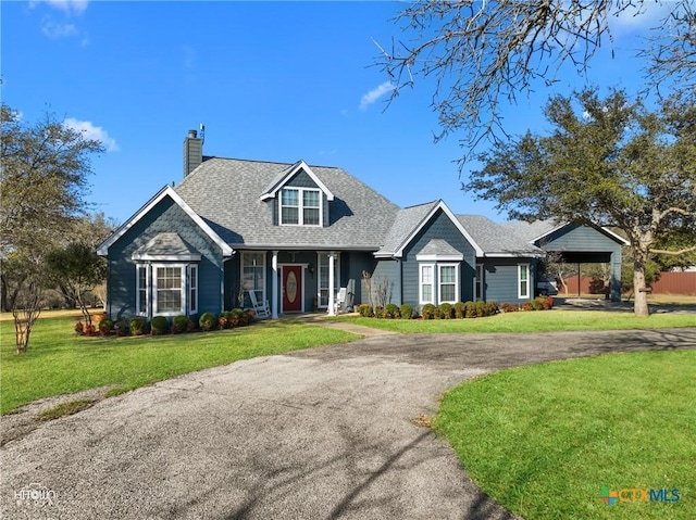 view of front of house featuring aphalt driveway, a chimney, a front lawn, and a shingled roof