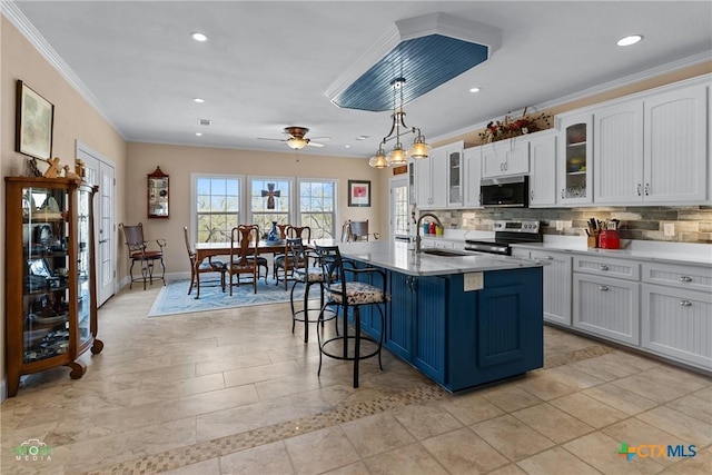 kitchen with a sink, appliances with stainless steel finishes, white cabinetry, a kitchen breakfast bar, and backsplash