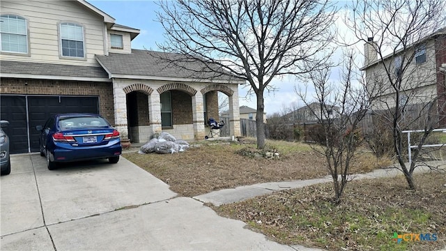 view of front of home featuring an attached garage, covered porch, brick siding, concrete driveway, and roof with shingles