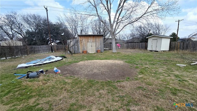 view of yard featuring an outbuilding, a fenced backyard, and a storage unit