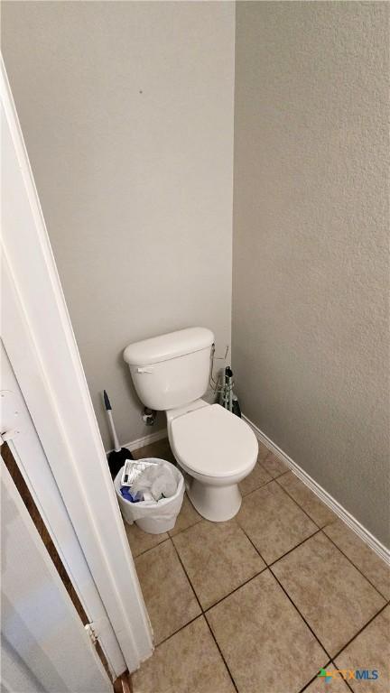 bathroom with toilet, tile patterned flooring, and baseboards