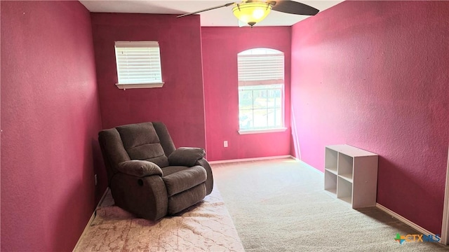 sitting room with carpet, baseboards, a ceiling fan, and a textured wall