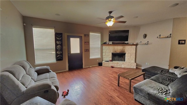 living room with a fireplace, wood finished floors, a ceiling fan, and baseboards