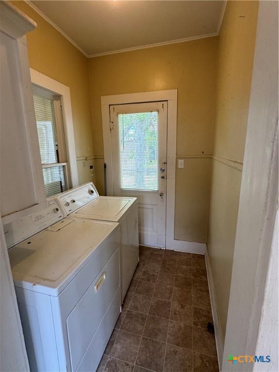 washroom with laundry area, baseboards, crown molding, and washing machine and clothes dryer