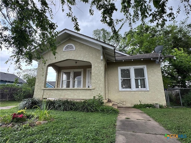 view of front facade with fence, a front yard, and stucco siding