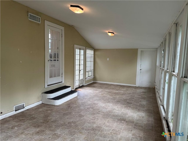 spare room featuring visible vents, baseboards, and lofted ceiling