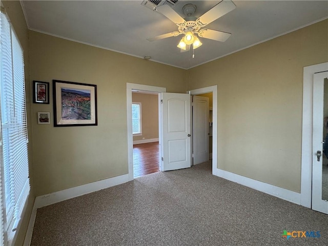 unfurnished bedroom featuring baseboards, ornamental molding, carpet floors, and visible vents