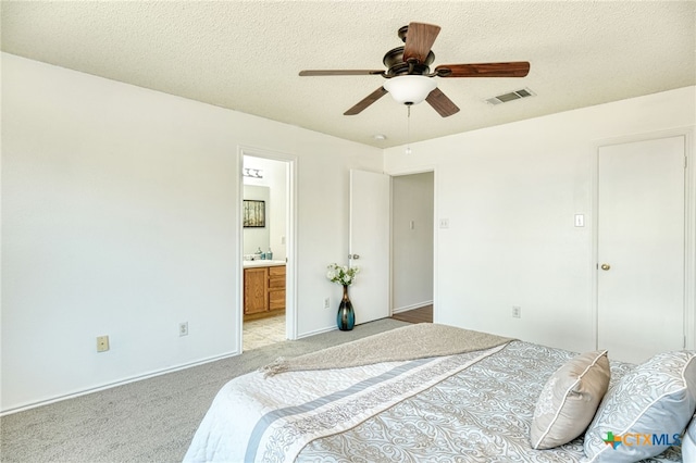 bedroom with ensuite bathroom, ceiling fan, light carpet, and a textured ceiling