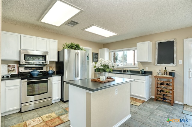 kitchen with sink, white cabinets, stainless steel appliances, and a textured ceiling