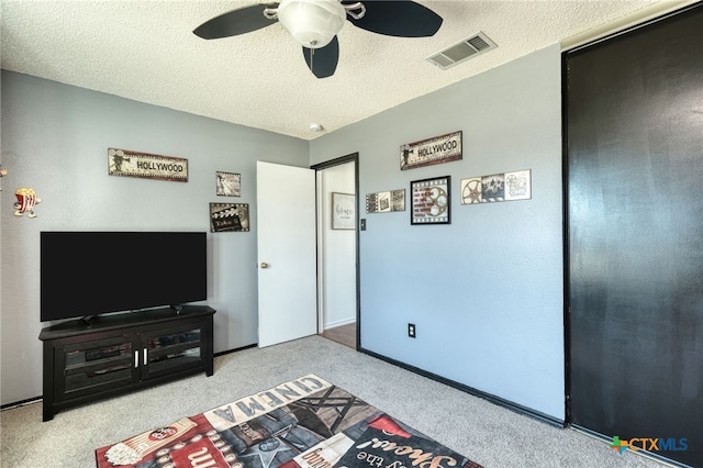 carpeted bedroom with ceiling fan and a textured ceiling