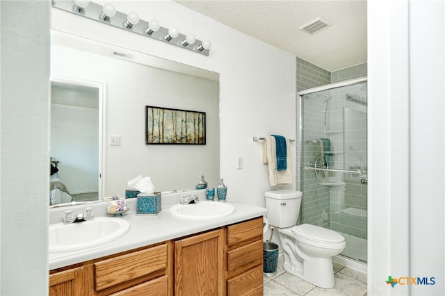 bathroom featuring a textured ceiling, vanity, tile patterned flooring, toilet, and a shower with shower door