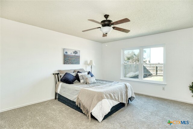 carpeted bedroom with ceiling fan and a textured ceiling